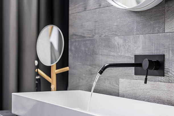 Modern white washbasin with black tap mounted to wall