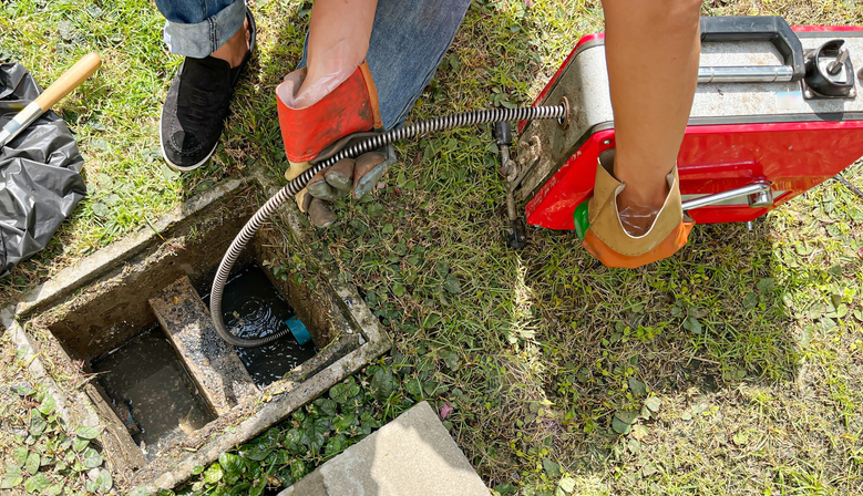 Clearing an outside drain blocked with fat with a electric plumber's snake.