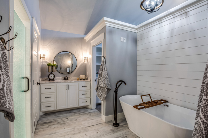 Light and bright bathroom with shiplap walls and round mirror